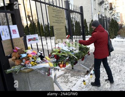 KIEV, UKRAINE - 8 FÉVRIER 2023 - Un homme laisse des œillets rouges en souvenir des victimes du tremblement de terre à l'extérieur de l'ambassade de la République de Turquie Banque D'Images