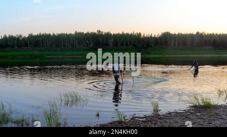 Deux hommes Yakuts et une fille gracieuse dans un châle pour aller barboter bottes dragnet pour la faune dans la rivière Vilyuy dans une forêt traditionnellement de capture de poissons locaux Banque D'Images