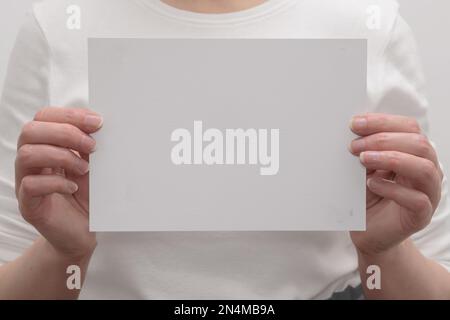 Les mains des femmes tiennent une feuille de papier vierge. maquette pour les informations sur l'agenda ou l'activité. Banque D'Images