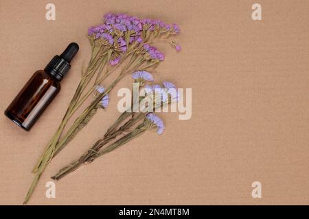 un bouquet de fleurs avec un flacon compte-gouttes. Motif de fleurs séchées sur fond papier. une pose à plat et une vue de dessus. Concept de médecine alternative Banque D'Images