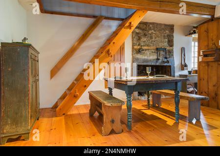 Table papillon en bois de pin antique de 1850s ensemble avec des plats à manger en étain et des bancs dans la salle à manger coin cuisine à l'intérieur de l'ancienne maison de 1750s. Banque D'Images