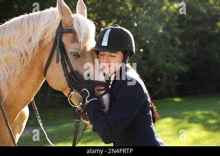 Jeune femme en costume d'équitation et son bel animal de compagnie à l'extérieur le jour ensoleillé Banque D'Images