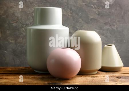 Élégants vases en céramique vides sur table en bois sur fond gris Banque D'Images