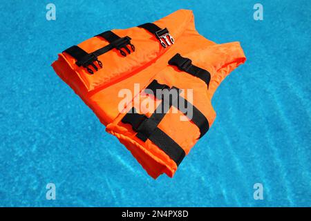 Gilet de sauvetage orange vif flottant dans la piscine Banque D'Images