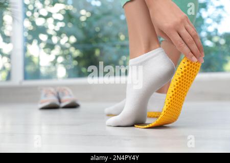 Femme qui pose une semelle intérieure orthopédique à l'intérieur, gros plan. Soins des pieds Banque D'Images