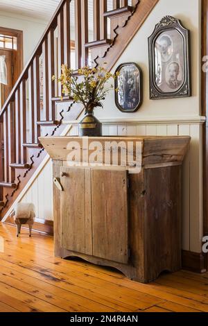 Petite armoire en bois antique à côté de l'escalier en bois de pin teinté brun dans la salle à manger à l'intérieur de la vieille maison de 1892. Banque D'Images