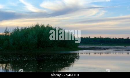 Silhouette d'une voiture sur les rives de la rivière Viluy au coucher du soleil sous le ciel bleu de la forêt d'épicéa. Banque D'Images