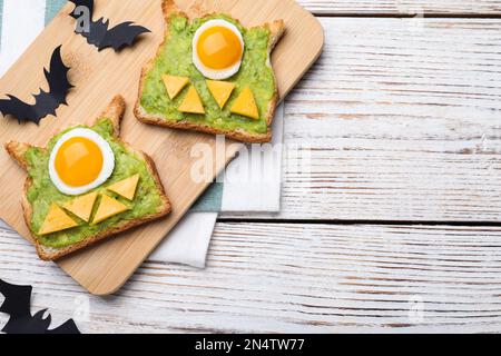 Petit-déjeuner sur le thème de l'Halloween servi sur une table en bois blanc, sur une table plate et sur un espace pour le texte. Délicieux sandwiches avec œufs frits Banque D'Images