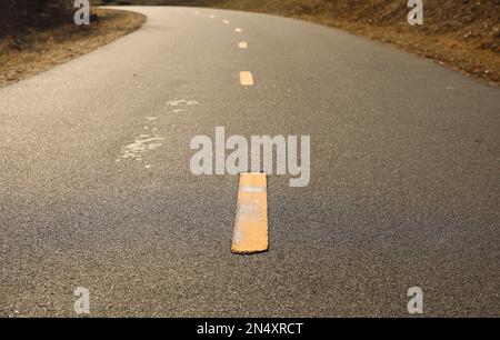 Piste cyclable au coucher du soleil sur une longue route Banque D'Images