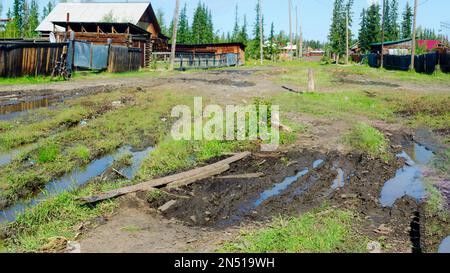 Le pont d'un conseil traverse une flaque pour le passage des piétons dans la rue du village au nord de l'ulus de Yakutia, Suntar Bright Day a Banque D'Images