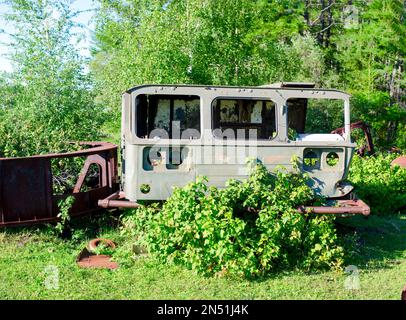 Le vieux corps rouillé de la cabine de la voiture soviétique se trouve sur l'herbe verte dans le champ près de la forêt dans la taïga du nord de Yakutia. Banque D'Images