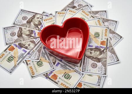 pour l'amour de l'argent coeur de forme cent billets de dollars sur fond blanc bol rouge Banque D'Images