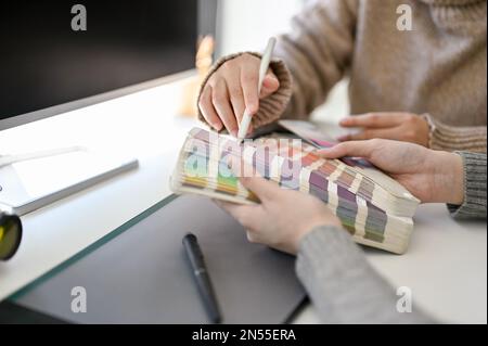 Deux graphistes créatifs discutent et choisissent la couleur sur la palette de couleurs pour leur projet, travaillant ensemble au bureau. image rognée Banque D'Images