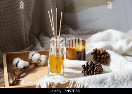 Désodorisant Reed, bougie et cônes de pin sur plateau en bois à l'intérieur Banque D'Images