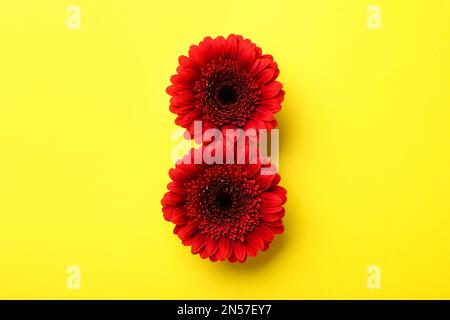 8 Mars carte de voeux motif avec gerberas rouges sur fond jaune, plat. Journée internationale de la femme Banque D'Images