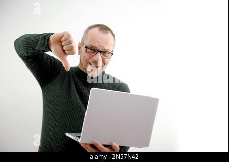 homme adulte en lunettes avec ordinateur portable sur fond blanc montre pouces vers le bas il est heureux qu'il a battu quelqu'un de surperformance dans la compétition a gagné s'est avéré être moins satisfait du concept de bureau de la victoire Banque D'Images