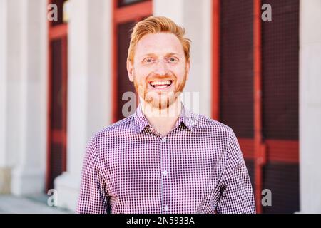 Gros plan Portrait de Happy Redhead Homme en train de regarder un sourire à l'appareil photo debout à l'extérieur. Photo de haute qualité Banque D'Images
