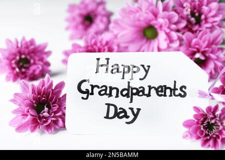 Belles fleurs et carte avec phrase heureux grands-parents jour sur table blanche, gros plan Banque D'Images