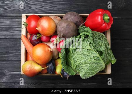 Caisse pleine de différents légumes et fruits sur table en bois noir, vue du dessus. Temps de récolte Banque D'Images