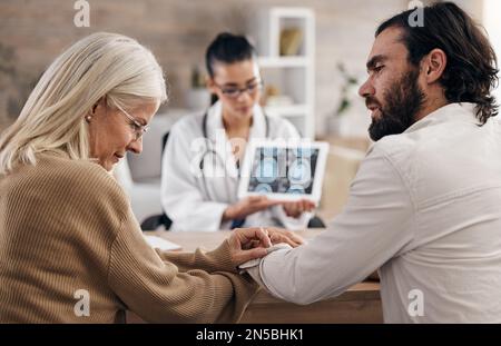 Cerveau, scanner et médecin avec la mère et le fils pour les résultats d'irm ou le diagnostic de rayons X pour le cancer sur comprimé. Soins de santé, conseils et patient dans le bureau des médecins Banque D'Images