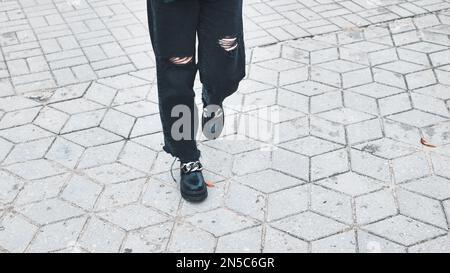 Une fille en jeans déchirés marche à travers la ville. Banque D'Images