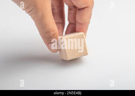 Ramasser à la main des blocs carrés en bois vides sur fond blanc. Banque D'Images