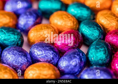 Grande pile d'œufs de pâques en chocolat enveloppés de couleurs, concept de Pâques festif brillant, macro de bonbons en gros plan joyeuses pâques Banque D'Images