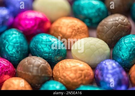 Grande pile d'œufs de pâques en chocolat enveloppés de couleurs, concept de Pâques festif brillant, macro de bonbons en gros plan joyeuses pâques Banque D'Images