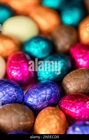 Grande pile d'œufs de pâques en chocolat enveloppés de couleurs, concept de Pâques festif brillant, macro de bonbons en gros plan joyeuses pâques Banque D'Images