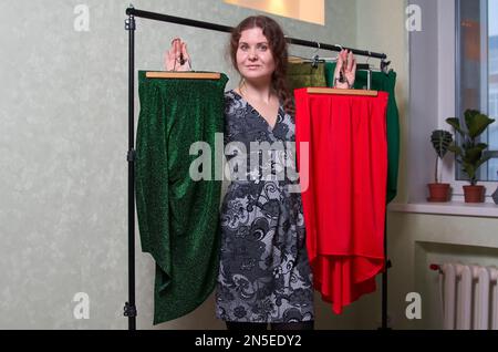 Femme dans le dressing choisir entre une jupe rouge et verte Banque D'Images