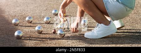 Jeu de pétanque, femme mesurant la distance de la boule de pétanque sur le terrain de pétanque, décidant qui est le gagnant Banque D'Images