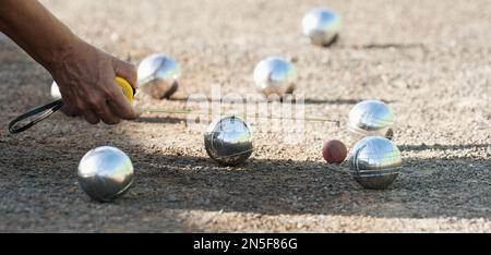 Jeu de pétanque, femme mesurant la distance de la boule de pétanque sur le terrain de pétanque, décidant qui est le gagnant Banque D'Images