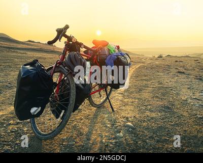 Equipé de sacs, le vélo rouge se dresse sur le côté de la route, entouré de montagnes, dans la campagne du parc national de Vinshlovani. Vacances de vélo à Geo Banque D'Images
