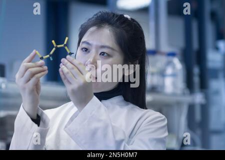 Jeune scientifique féminine examinant le modèle moléculaire dans un laboratoire, Freiburg im Breisgau, Bade-Wurtemberg, Allemagne Banque D'Images