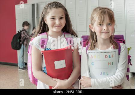 Portrait de deux écolières portant des sacs à dos dans un couloir près des casiers, Bavière, Allemagne Banque D'Images