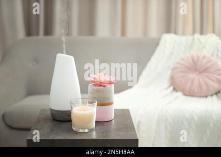 Diffuseur d'huile aromatique et bougie sur table dans la chambre Banque D'Images