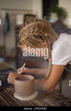 La fille travaille avec de l'argile céramique dans un atelier de poterie moderne. Table de cuisson Banque D'Images