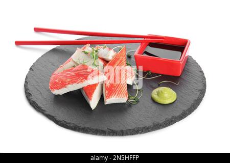 Assiette en ardoise avec bâtonnets de crabe frais et sauce soja sur fond blanc Banque D'Images