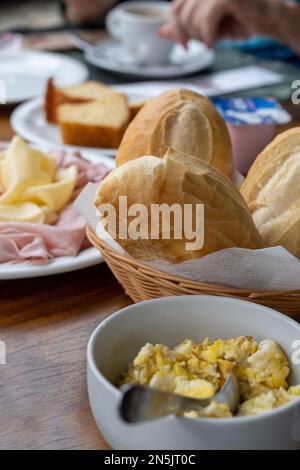 Le concept brésilien du petit déjeuner dans un cadre de restaurant montrant la main d'une femme non identifiée, hors foyer et méconnaissable, à côté d'une tasse de café Banque D'Images