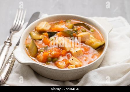 Délicieux calamar de ragoût avec légumes dans un bol avec fourchette et couteau Banque D'Images