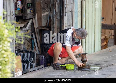 SAMUT PRAKAN, THAÏLANDE, FÉVRIER 04 2023, l'homme dans la rue nettoie le plateau avec un piédestal pour pratiquer le bouddhisme Banque D'Images