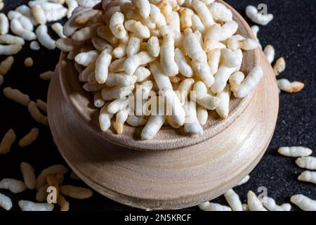 Riz soufflé dans un bol en bois isolé sur fond noir Banque D'Images