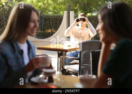 Un homme jaloux qui espionne une ex-petite amie dans un café en plein air Banque D'Images