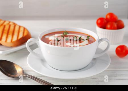 Soupe de tomates fraîches dans un bol blanc sur fond de bois. Vue latérale. copier l'espace Banque D'Images