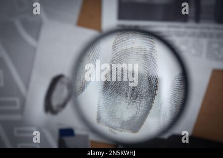 Regarder à travers la loupe les empreintes digitales sur le tableau de détective, gros plan Banque D'Images