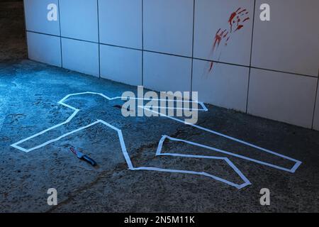 Scène de crime avec le contour de craie, le couteau et les marques de sang sur le sol. Enquête de détective Banque D'Images