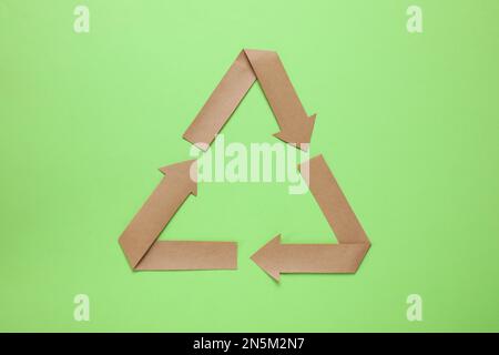 Symbole de recyclage coupé en papier sur fond vert, vue de dessus Banque D'Images