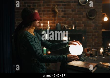 Jeune femme aveuglée tenant la main sur la boule spirituelle de cristal Banque D'Images