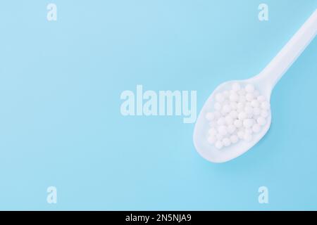 Cuillère de globules homéopathiques sur fond bleu. Alternative homéopathie médecine herbes, soins de santé et pilules. copier l'espace pour le texte. Banque D'Images