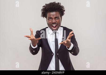 L'homme émotionnel hurle fort, ouvre la bouche largement, se sent désespéré après avoir découvert des événements tragiques, en portant une chemise blanche et tuxedo. Prise de vue en studio isolée sur fond gris. Banque D'Images